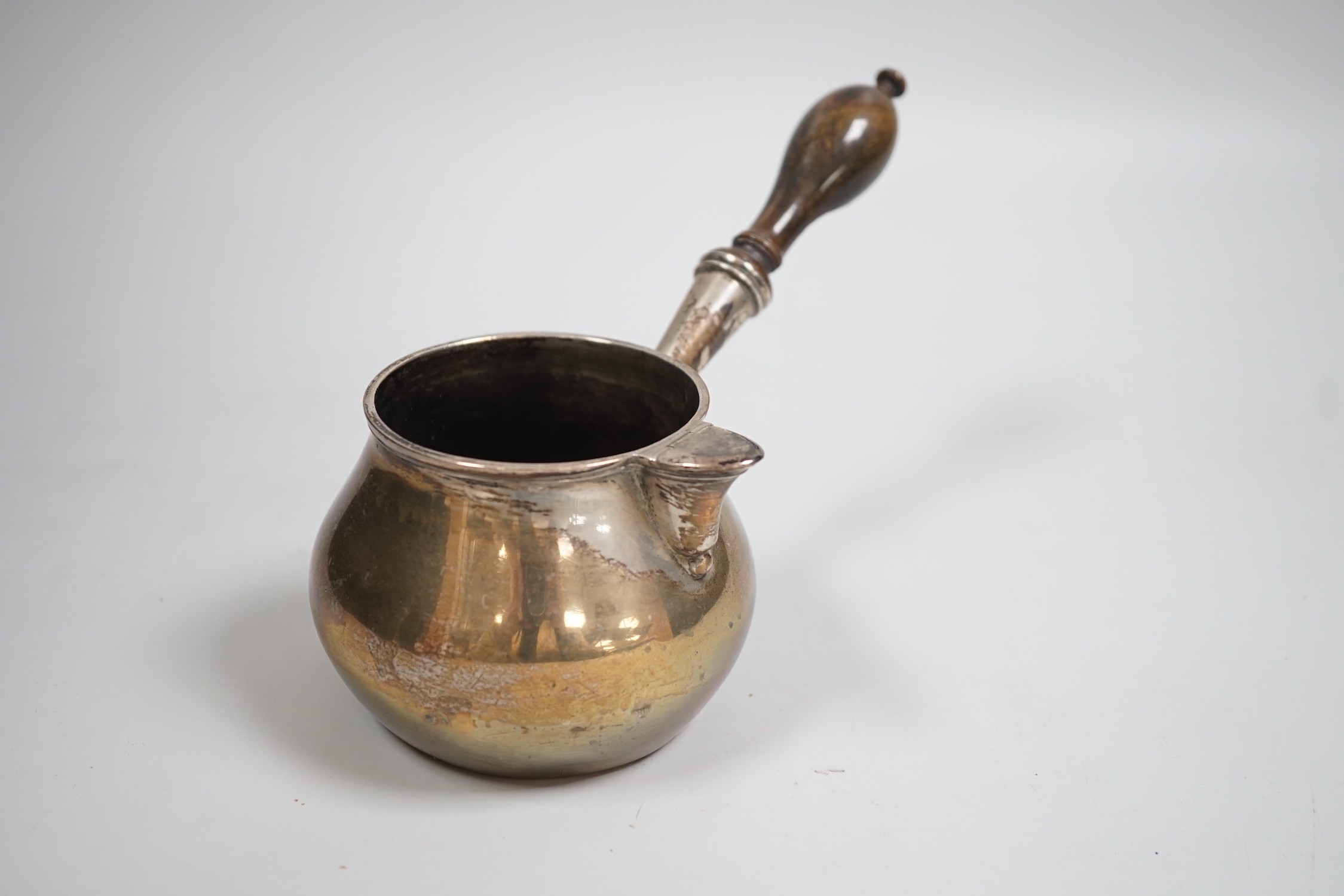 A late 18th/early 19th century white metal brandy warmer, with turned wooden handle and spout with hinged cover, stamped JH below an anchor, approx. 20cm in length, handle (a.f.).
